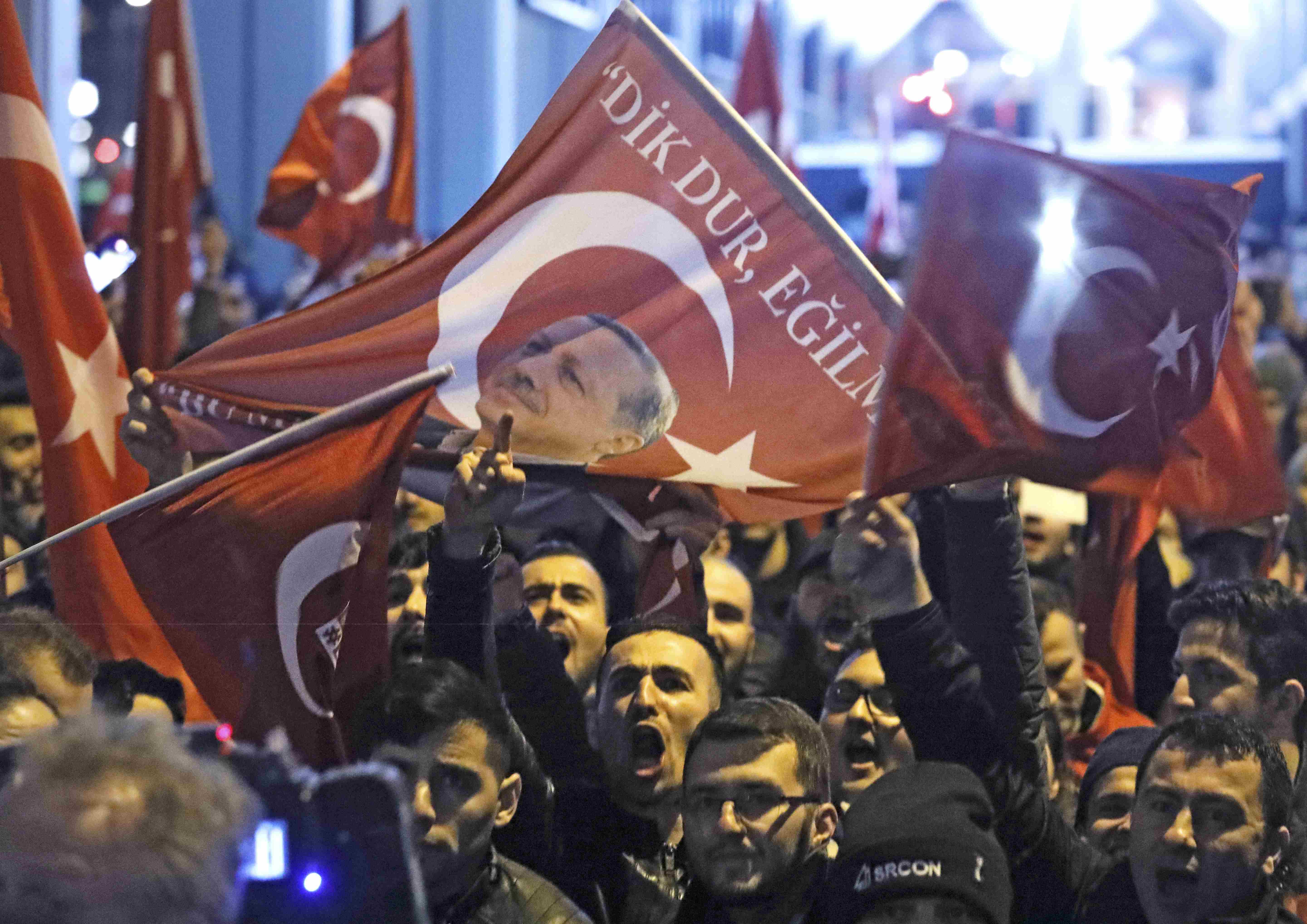 旅居荷兰的土耳其人周六晚在土耳其驻鹿特丹领事馆外，高举土耳其国旗和印有总统埃尔多安肖像的布条示威。-路透社-
