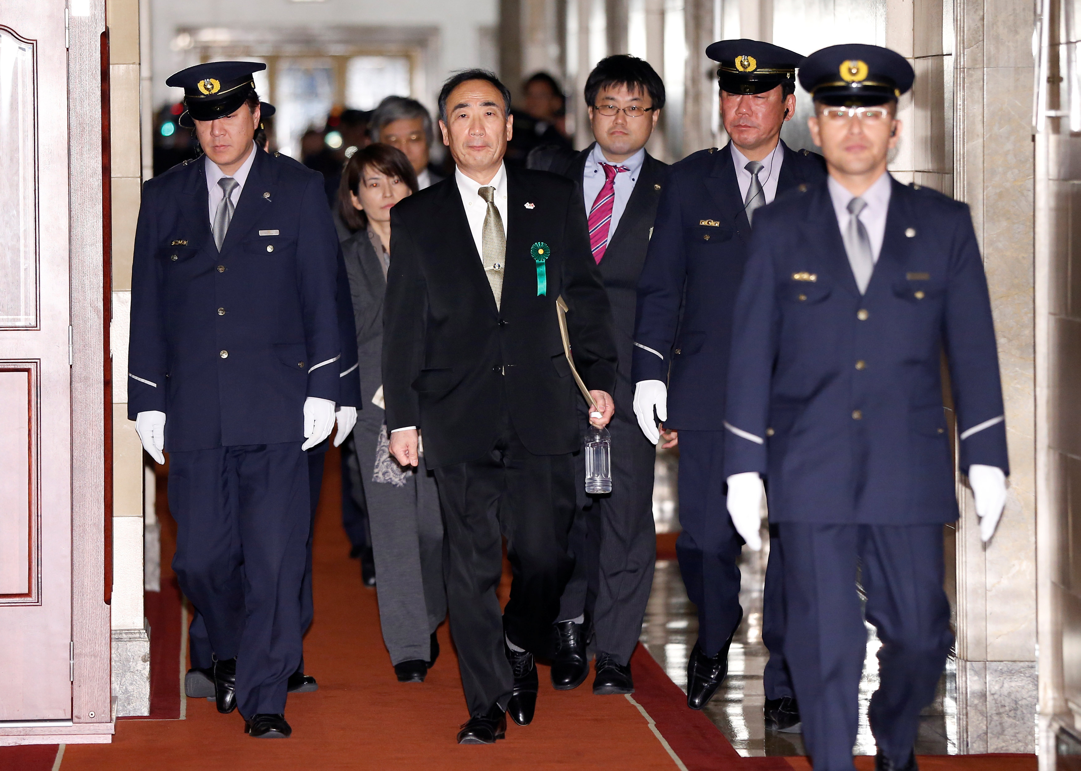 Yasunori Kagoike (C), head of Moritomo Gakuen, is escorted by security officers as he leaves a parliamentary session for his testimony in Tokyo, Japan March 23, 2017. REUTERS/Issei Katon
