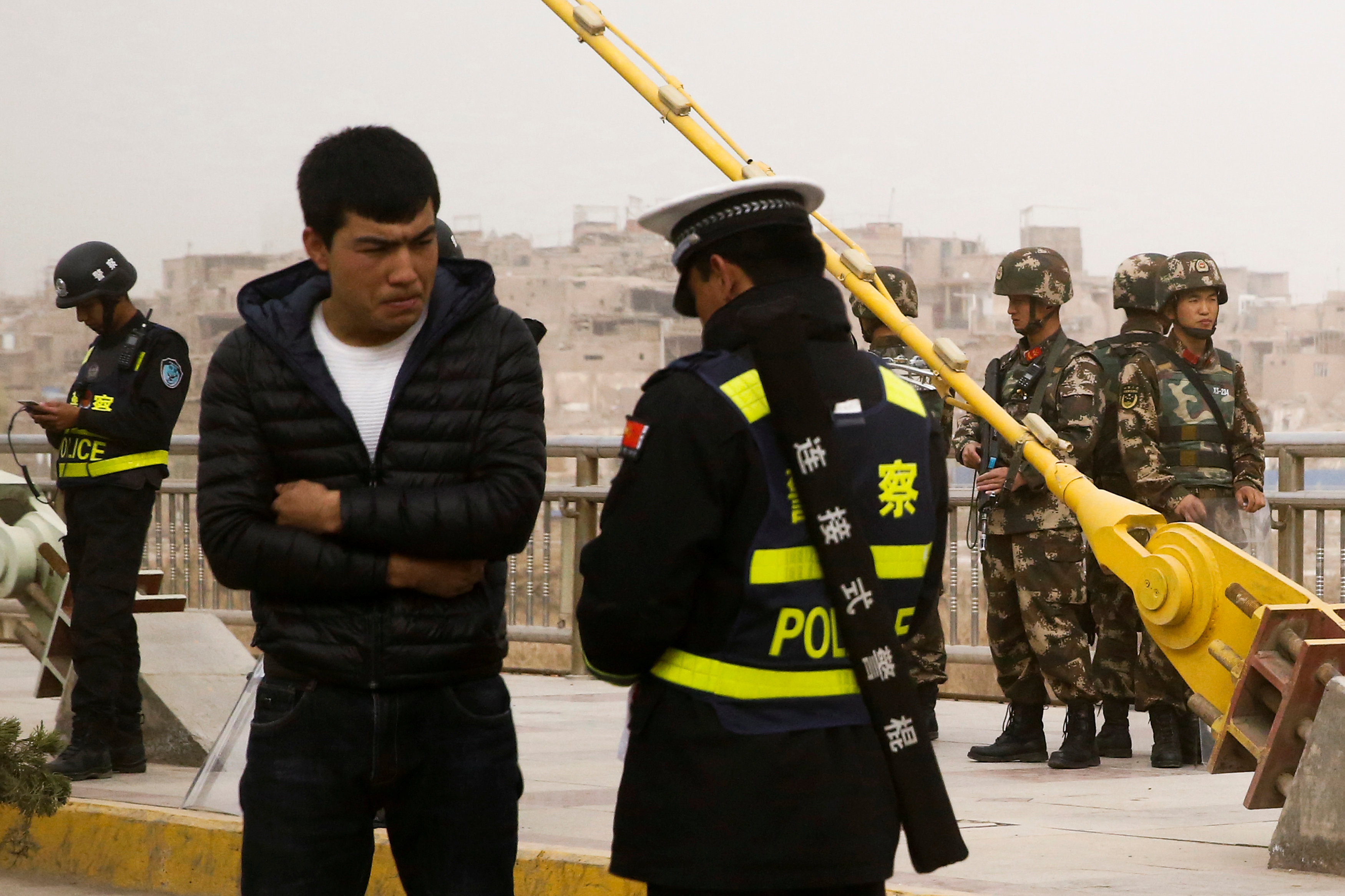 A police officer checks the identity card of a man as security forces keep watch in a street in Kashgar, Xinjiang Uighur Autonomous Region, China, March 24, 2017. REUTERS/Thomas Peter SEARCH ,XINJIANG PETER, FOR THIS STORY. SEARCH ,WIDER IMAGE, FOR ALL ST