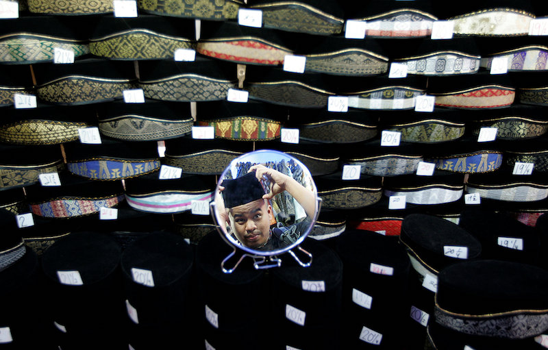 A man is reflected in a mirror as he tries on a songkok at a shop in Kuala Lumpur March 20, 2017. u00e2u20acu201d Reuters pic