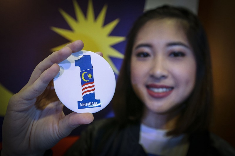 Yvonne Lee Hui Lee from the Lim Kok Wing choir holds a button with the new 1Malaysia Negaraku logo during the launch event in Putrajaya August 23, 2017. u00e2u20acu201d Picture by Yusof Mat Isa