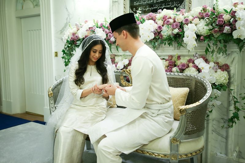 Dennis Muhammad Abdullah (right) of the Netherlands places the ring on the finger of his bride, Princess Tunku Tun Aminah Sultan Ibrahim (left), the only daughter of the Sultan of Johor, after their wedding at Istana Bukit Serene in Johor Baru
