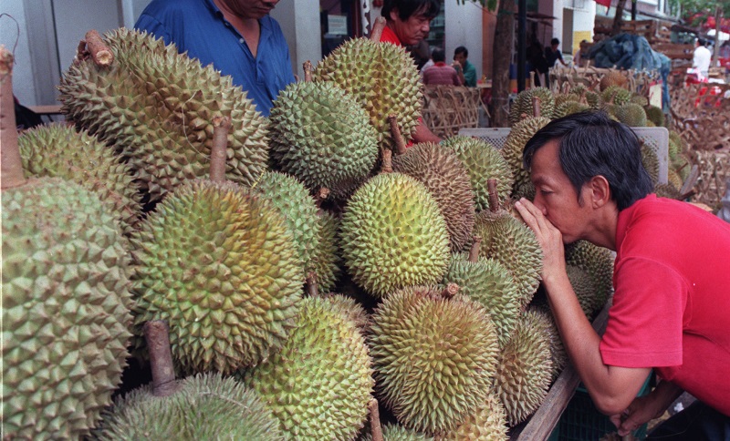 FILE PHOTO: A customer leans forward to smell the ,king of fruits,, the exotic Asian durian in downtown Singapore on April 11, 1999. REUTERS/Simon Thong/File Photo