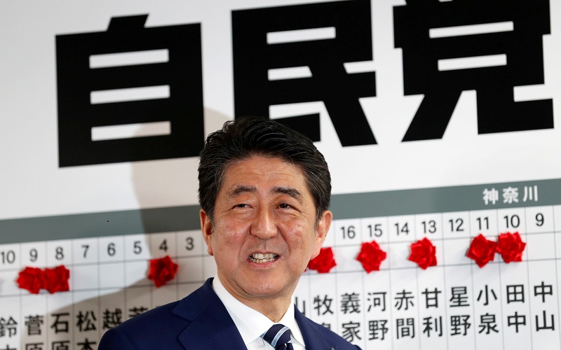 Japan's Prime Minister Shinzo Abe, leader of the Liberal Democratic Party (LDP), smiles as he puts a rosette on the name of a candidate who is expected to win the lower house election, at the LDP headquarters in Tokyo, Japan, October 22, 2017. REUTERS/Kim