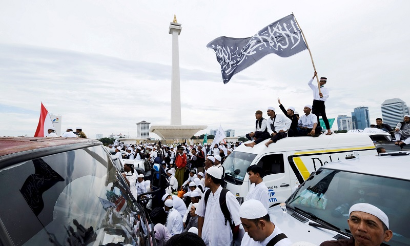 Members of Islamist groups wave flags during a rally at The National Monument compound as they celebrate the one-year anniversary of a protest that brought down former ethnic Chinese Jakarta governor Basuki Tjahja Purnama in Jakarta, Indonesia, December 2