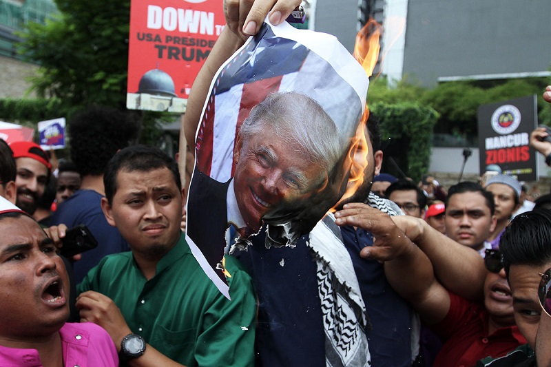 Protesters burn pictures of US President Donald Trump as they march towards the US embassy in Kuala Lumpur December 8, 2017. u00e2u20acu201d Picture by Miera Zulyanann