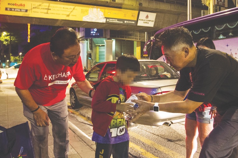 (From left) Redberry Chief Operating Executive, Datuk Wong Sai Wan and Redberry Ambient managing director Tho Tuck Wah helping to provide food to the homeless population around KL. u00e2u20acu201d Picture by Shafwan Zaidon
