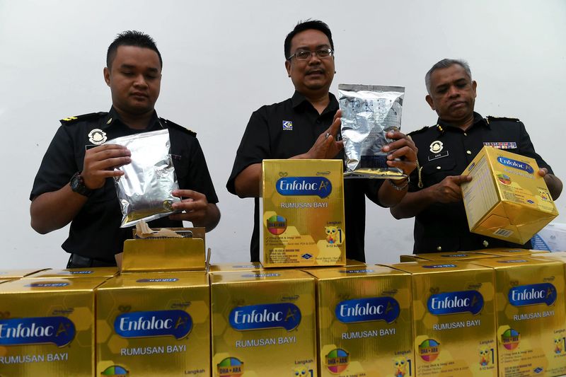 Johor Ministry of Domestic Trade, Cooperatives and Consumerism (KPDNKK) director Khairul Anwar Bachok (centre) showing confiscated branded baby milk formula, in Kulai, December 10, 2017. u00e2u20acu201d Bernama pic