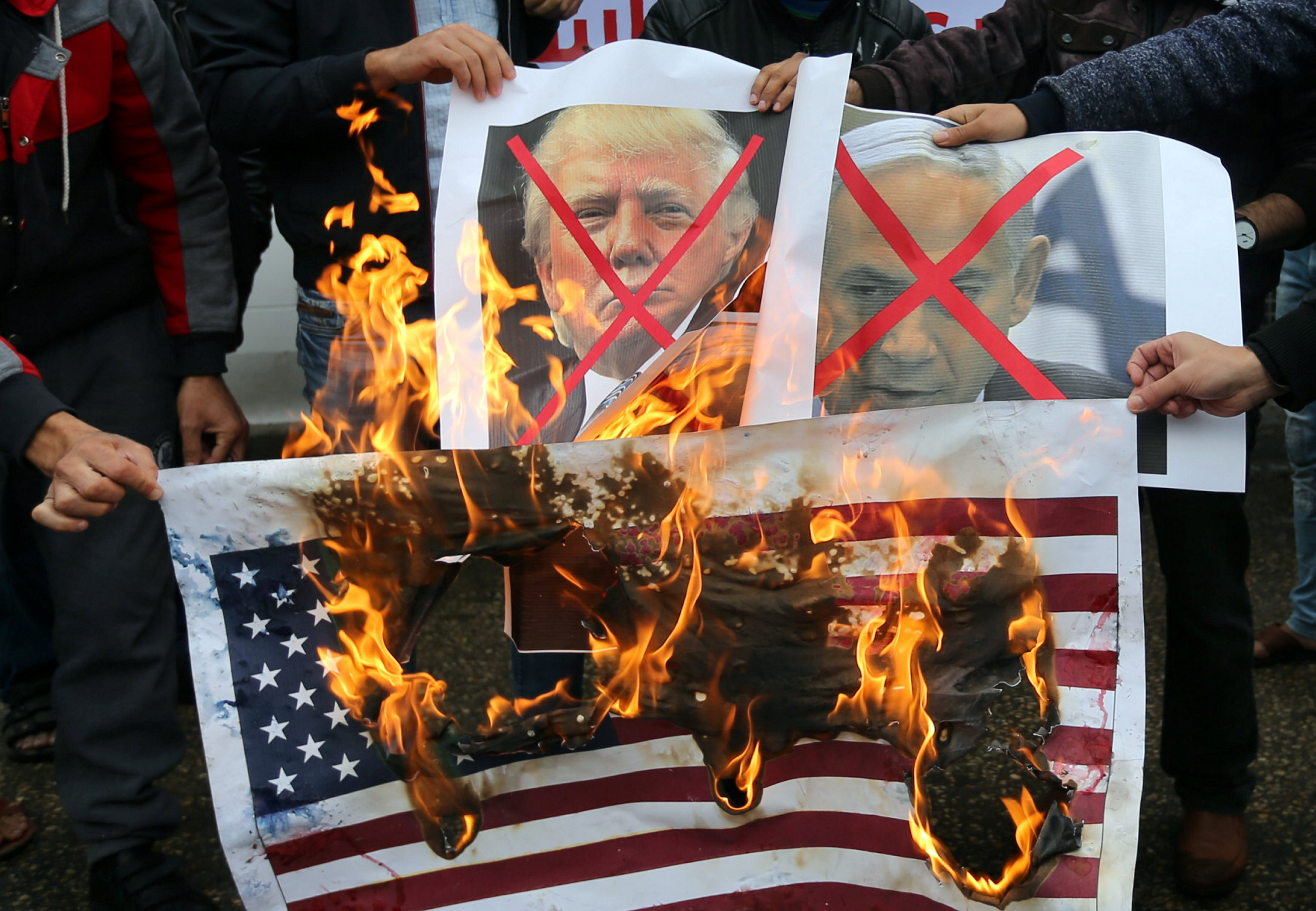 大批巴勒斯坦民众在加萨城示威，火烧美国国旗，以及特朗普和以色列总理内塔尼亚胡（右）的肖像。-路透社-