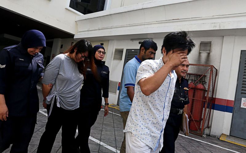 Lim Su-Quinn (in grey), 29 and Lim Keng Liang (front, in white), 37 are escorted by police officers to the lock up after they were charged with stealing a Buddha statue at the Malaysian Buddhist Association building in George Town December 26, 2017. u00e2u20acu2022 P