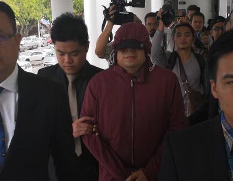 Former deputy director with Sabah Water Teo Chee Kong ( in maroon hoodie) being led to court this morning.