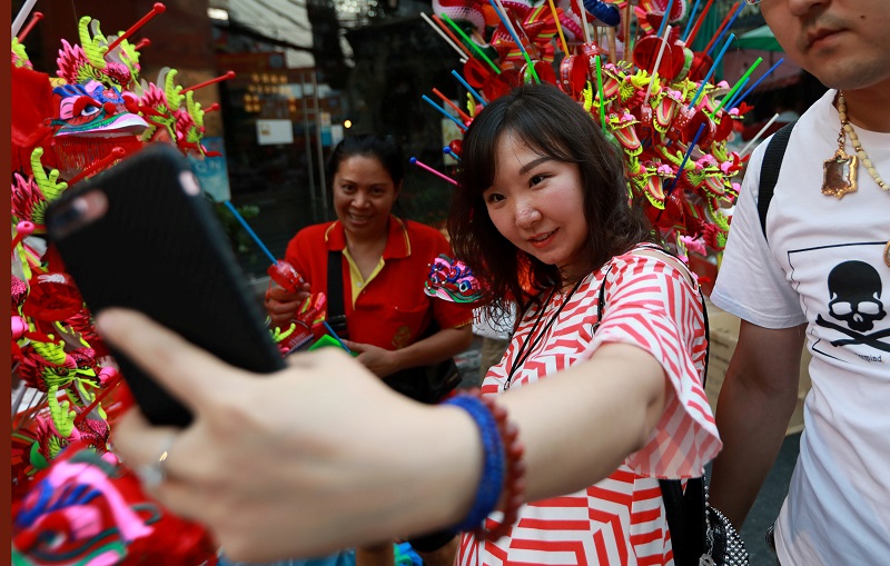 A Chinese tourist takes a selfie photo as she buys Chinese traditional dragon toys in Chinatwon in Bangkok February 16, 2018. u00e2u20acu201d Reuters pic