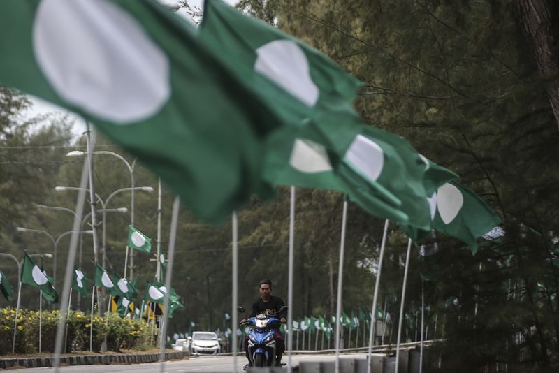 A motorcyclist rides past PAS and Barisan Nasional flags along Jalan Batu Buruk in Kuala Terengganu March 23, 2018. u00e2u20acu2022 Picture by Azneal Ishak