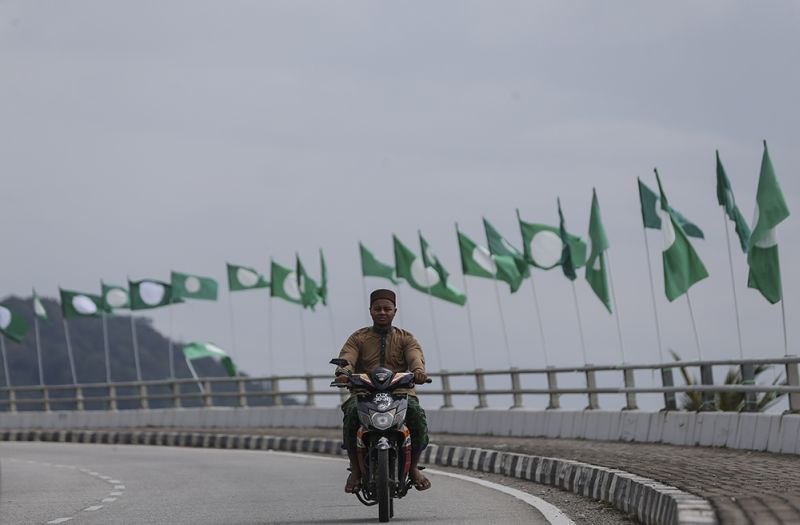 A motorcyclist rides past PAS and Barisan Nasional flags along Jalan Batu Buruk in Kuala Terengganu March 23, 2018. u00e2u20acu2022 Picture by Azneal Ishak