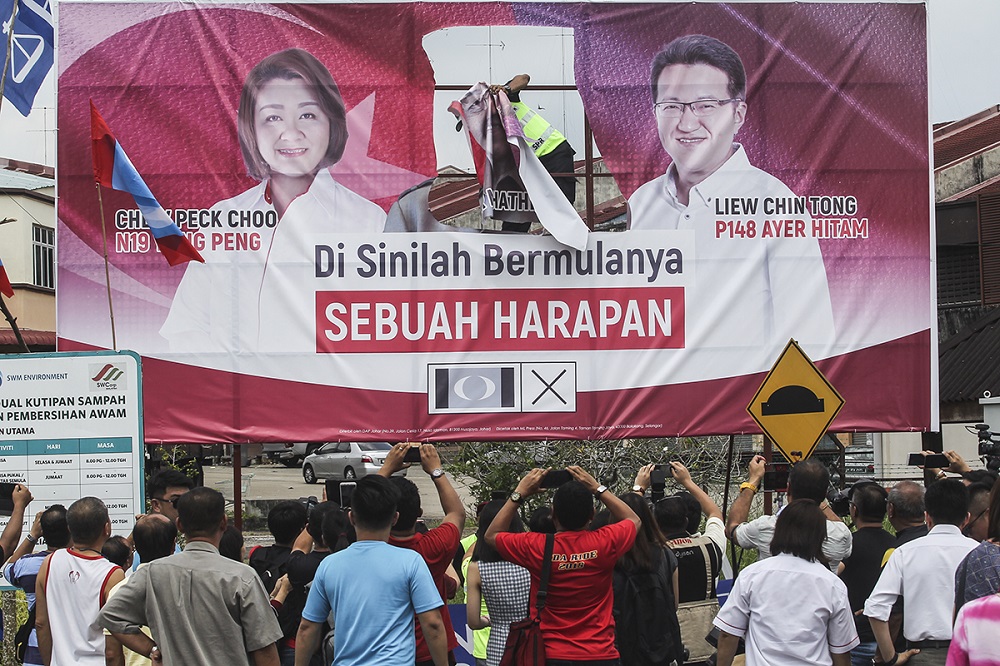 A Election Commissioner staff takes down a Pakatan Harapan billboard in Yong Peng April 30, 2018. u00e2u20acu201d Picture by Shafwan Zaidon