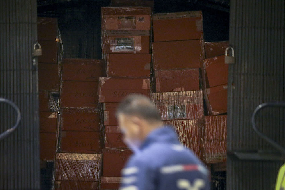 An investigator walks past sealed boxes believed to contain luxury designer bags in a Black Maria outside Pavilion Residences in Kuala Lumpur May 18, 2018. u00e2u20acu201d Picture by Hari Anggara  