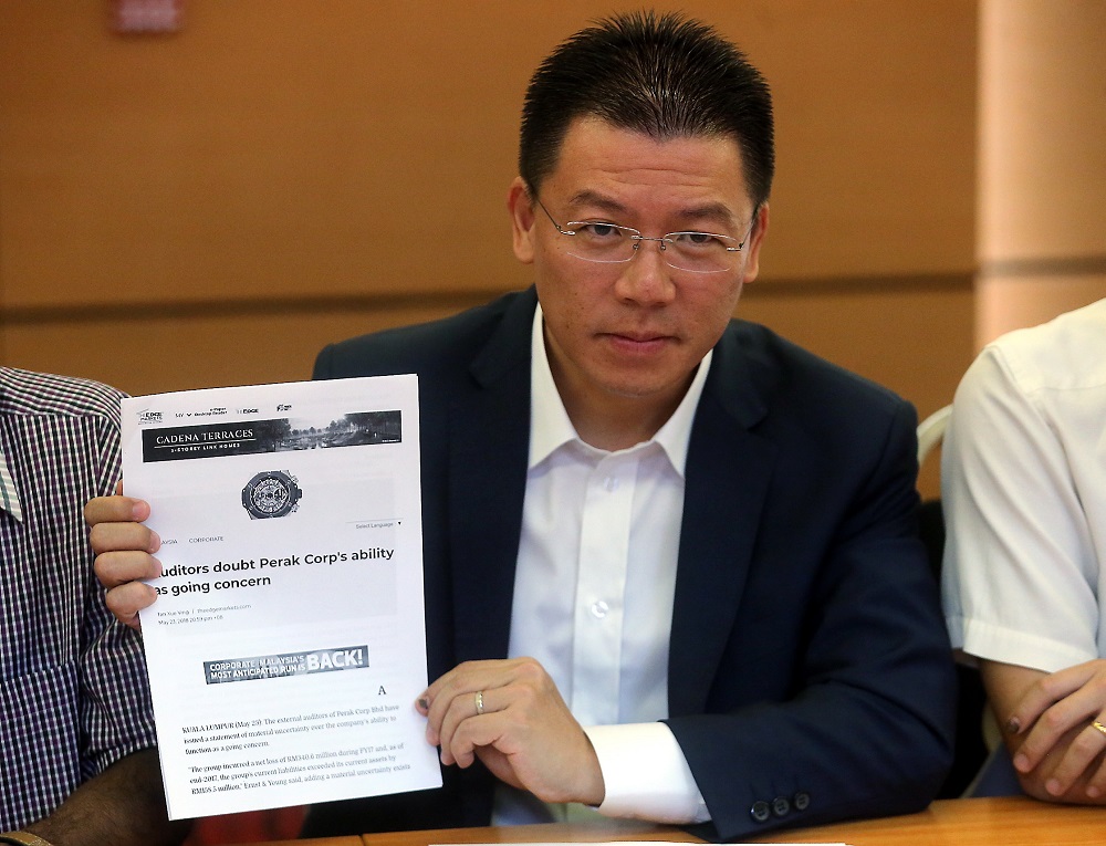 DAP's Nga Kor Ming shows a paper cutting of the Ernst & Young audit report on Perak Corp Bhd during a press conference in Ipoh May 26, 2018. u00e2u20acu201d Picture by Farhan Najib