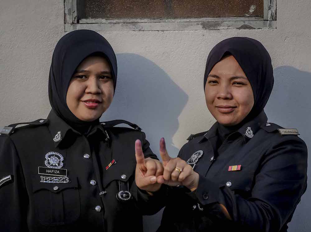 Police officers show their fingers marked with indelible ink after early voting for the 14th general election at Perumahan Polis Parit Perupok in Muar, Johor May 5, 2018. u00e2u20acu201d Picture by Firdaus Latif