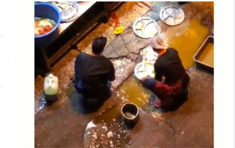 Screengrab of the restaurantu00e2u20acu2122s employees using water puddled beside a drain to clean dishes.