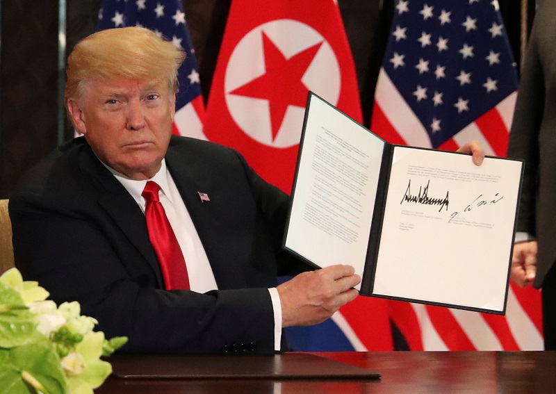 US President Donald Trump holds up a document signed by him and North Korea's leader Kim Jong-un following a signing ceremony during their historic US-North Korea summit, at the Capella Hotel on Sentosa island June 12, 2018. u00e2u20acu201d AFP pic