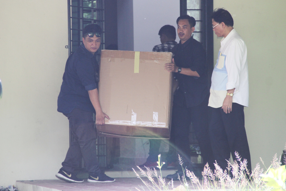 Several uniformed and plain-clothes police officers from Bukit Aman carting away several boxes after they raided a safe house believed to have been used by Datuk Seri Najib Razak in Putrajaya June 11, 2018. u00e2u20acu201d Picture by Azinuddin Ghazali