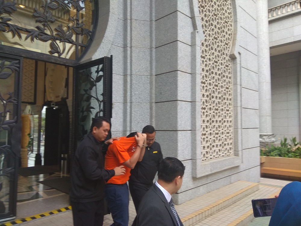 The ex-aide to former prime minister Datuk Seri Najib Razak (in handcuffs) is led out of the Magistratesu00e2u20acu2122 Court in Putrajaya June 25, 2016. u00e2u20acu201d Screen capture via Bernama video
