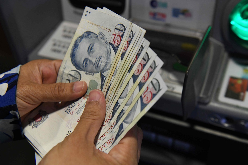 A customer withdraws Singapore dollar notes from an automated teller machine (ATM) in Singapore April 13, 2018. u00e2u20acu201d AFP pic