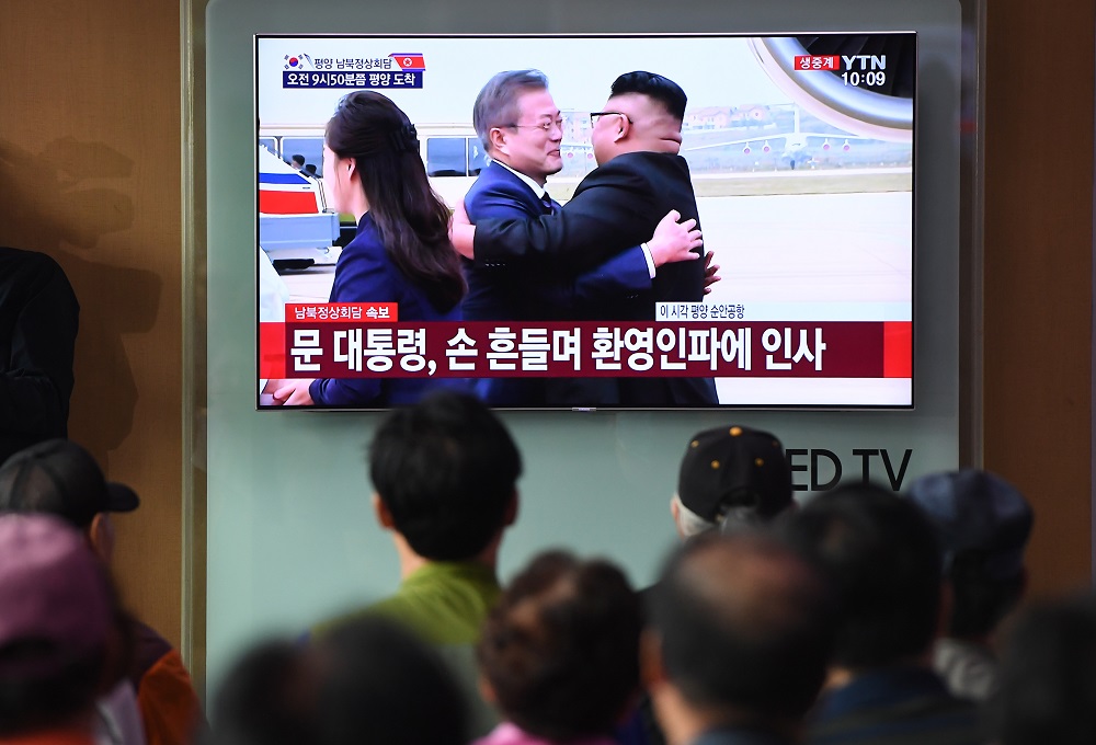 People watch a screen showing live footage of the arrival of South Korean President Moon Jae-in at Pyongyang airport as Moon Jae-in and North Korean leader Kim Jong-un hug, at a railway station in Seoul on September 18, 2018. u00e2u20acu201d AFP pic