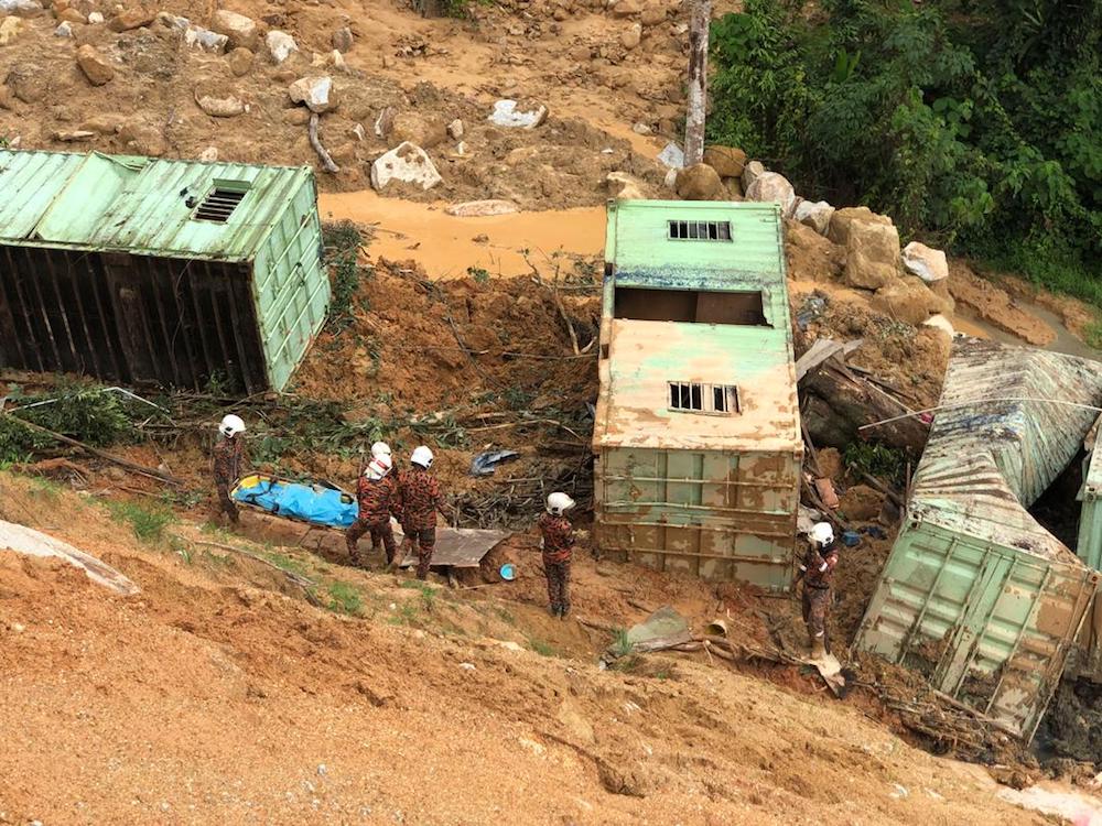 Fire and Rescue Department personnel remove a body at 3.40pm from the site of a landslide in Jalan Paya Terubong. u00e2u20acu201d Picture courtesy of Mohd Amirul Amir/RTM