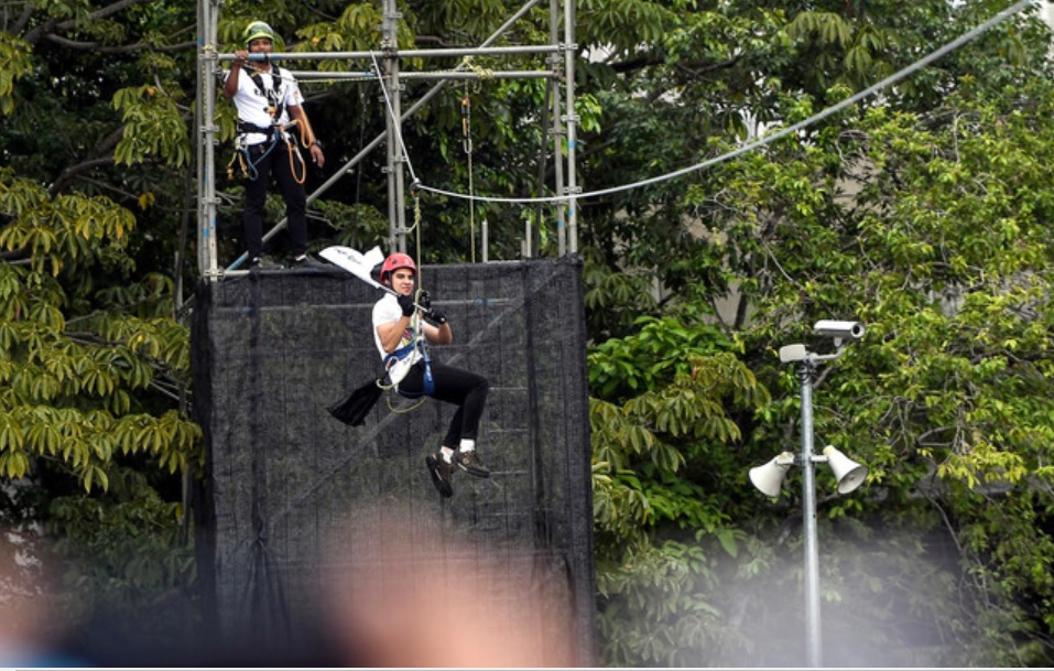 赛沙迪以极限运动“飞狐(Flying Fox)”方式将国家体育日旗帜带进会场。-马新社-