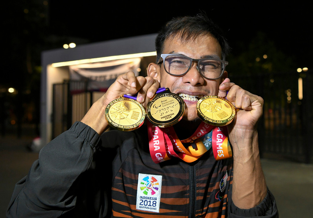 Mohamad Ridzuan Mohamad Puzi menunjukkan tiga pingat emas yang dimenangi di Temasya Sukan Para Asia 2018 di Stadium Gelora Bung Karno semalam. u00e2u20acu201d Foto Bernama
