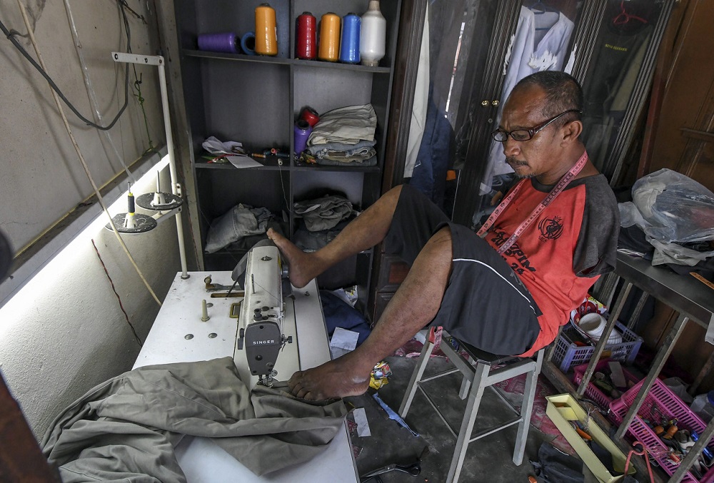 Rahim Yusof, 52, sedang menyiapkan pakaian yang dipesan oleh pelanggan di kedai jahitnya yang terletak di Pulai Chondong, Machang. u00e2u20acu201d Foto Bernama 