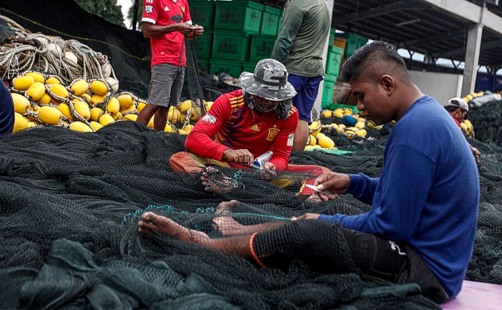 Fishermen are pictured mending their nets at the dock of the Fisheries Developement Authority of Malaysia in Batu Maung December 17, 2018.u00e2u20acu201d Picture by Sayuti Zainudin