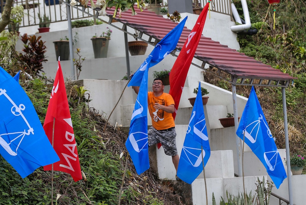 A Barisan Nasional supporter putting up flags of the coalition in Tringkap January 20, 2019. u00e2u20acu201d Picture by Farhan Najib