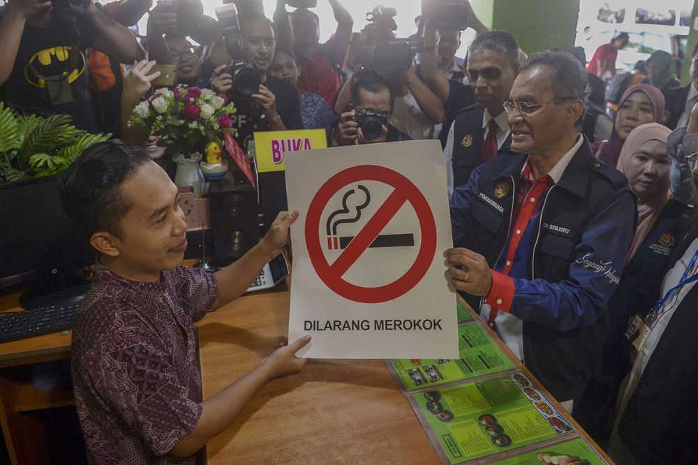 Health Minister Dzulkefly Ahmad hands over a no-smoking sign to the owner of an eatery in Kuala Lumpur January 1, 2018. u00e2u20acu2022 Picture by Mukhriz Hazim
