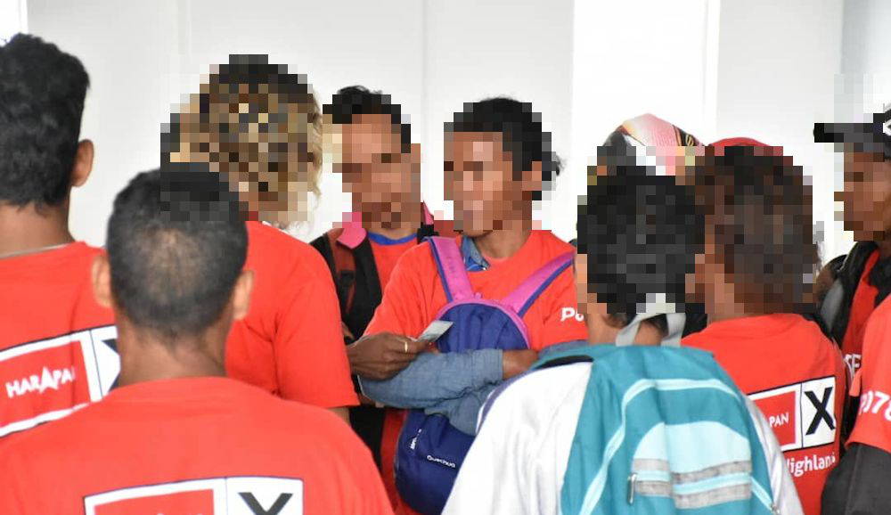A woman in a Pakatan Harapan shirt is seen giving out cash in a photo widely shared on social media.