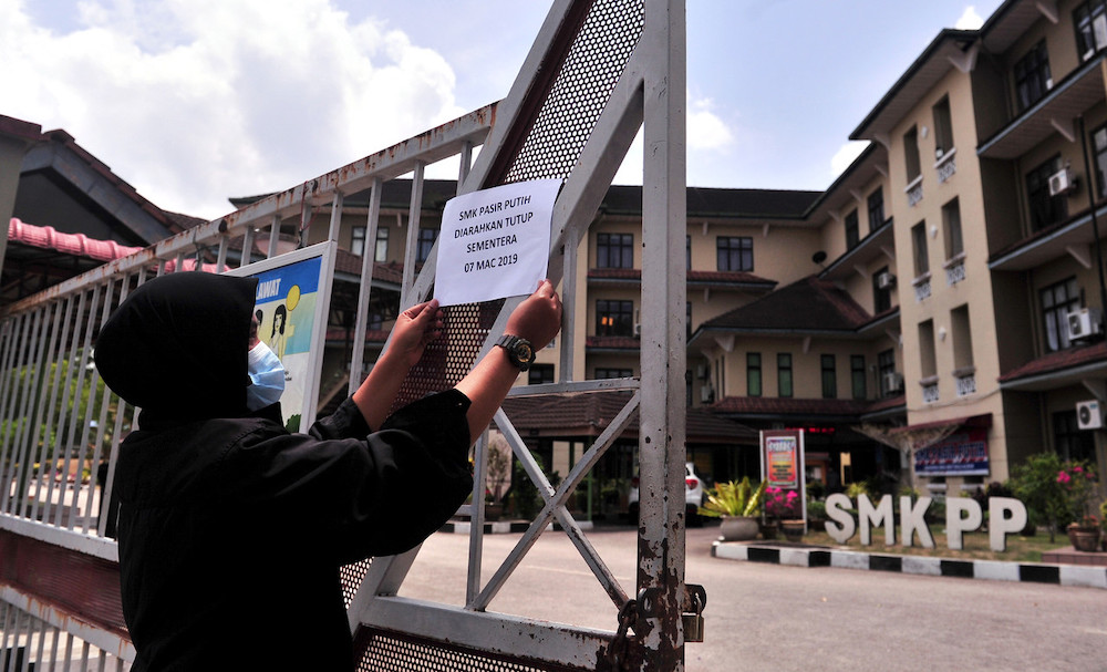 A notice being put up in front of SMK Pasir Putih to announce the temporary closure of the school due to toxic fumes from chemicals dumped into the nearby Sungai KimKim, March 7, 2019. u00e2u20acu201d Foto Bernama