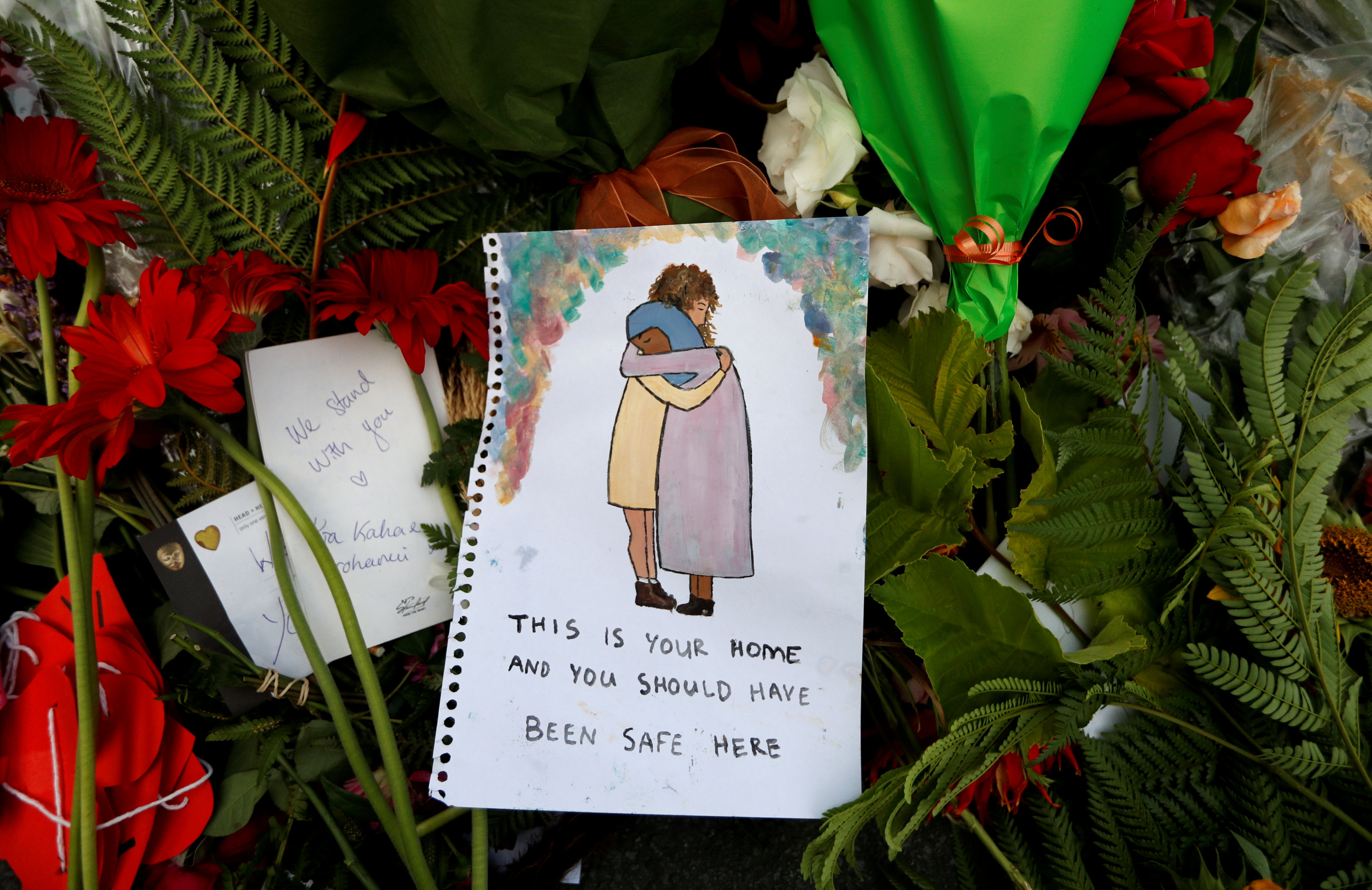在献给受害者的一片花海中，一张慰问手绘图上写着：“这里是你的家，你应该感到安全。”-路透社-