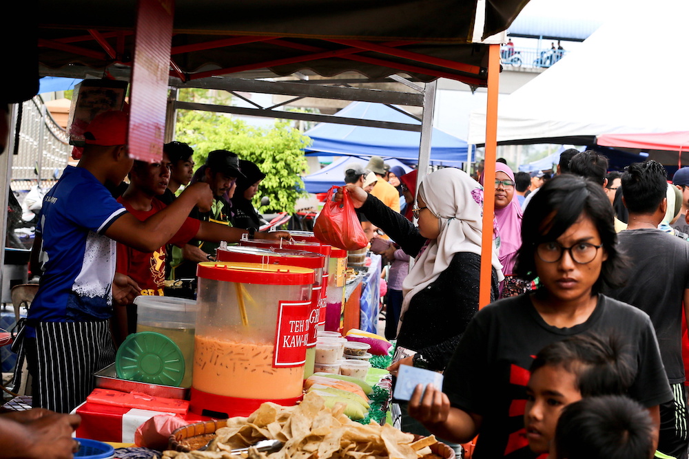 A customer buys a drink packed in single-use plastic at a Ramadan bazaar in Kampung Kanchong Darat. u00e2u20acu201d Picture by Sayuti Zainudin