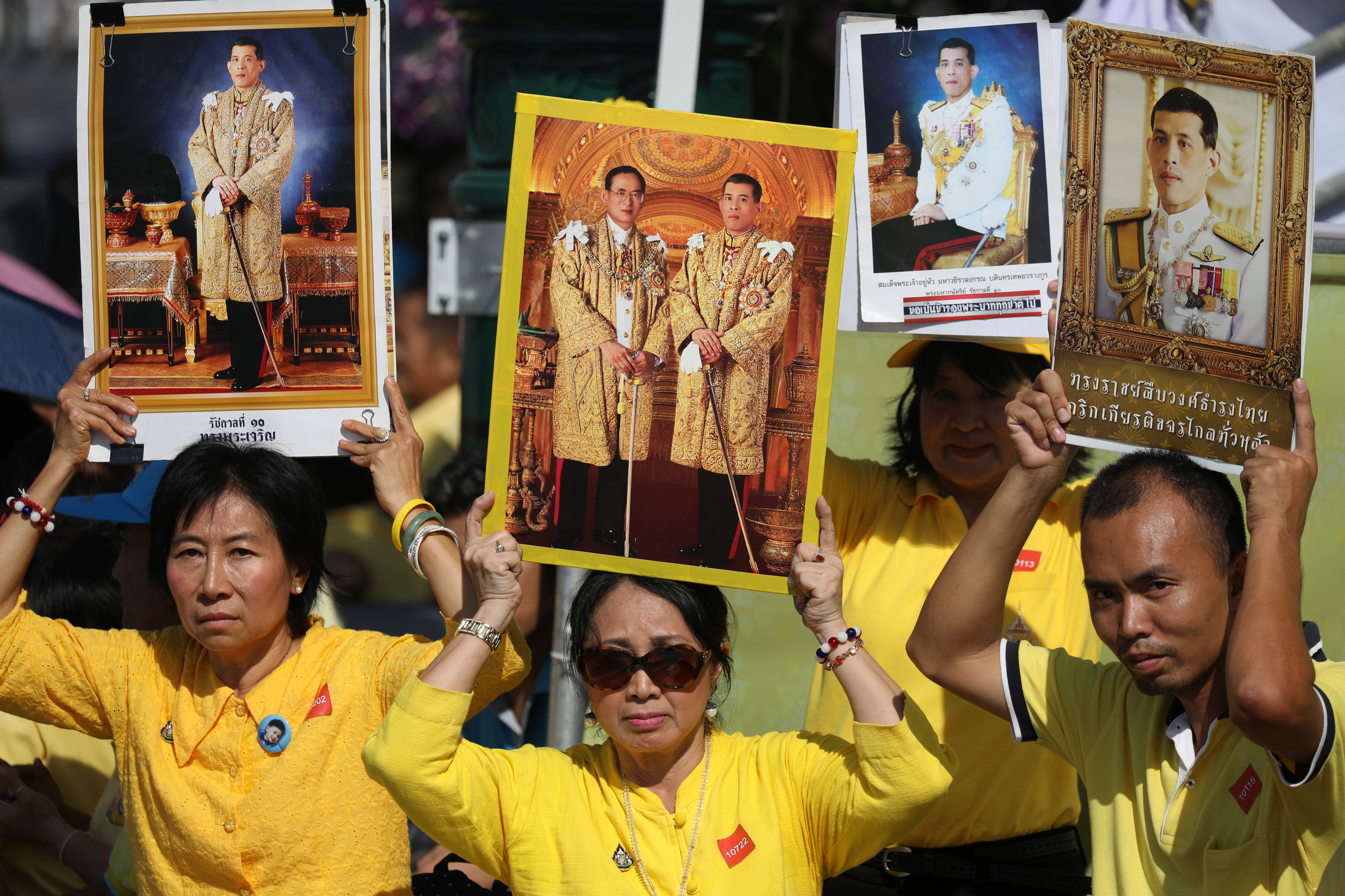 身穿黄衣的民众在大王宫外，高举已故泰王普密蓬和哇集拉隆功的照片，等待加冕仪式开始。-路透社-