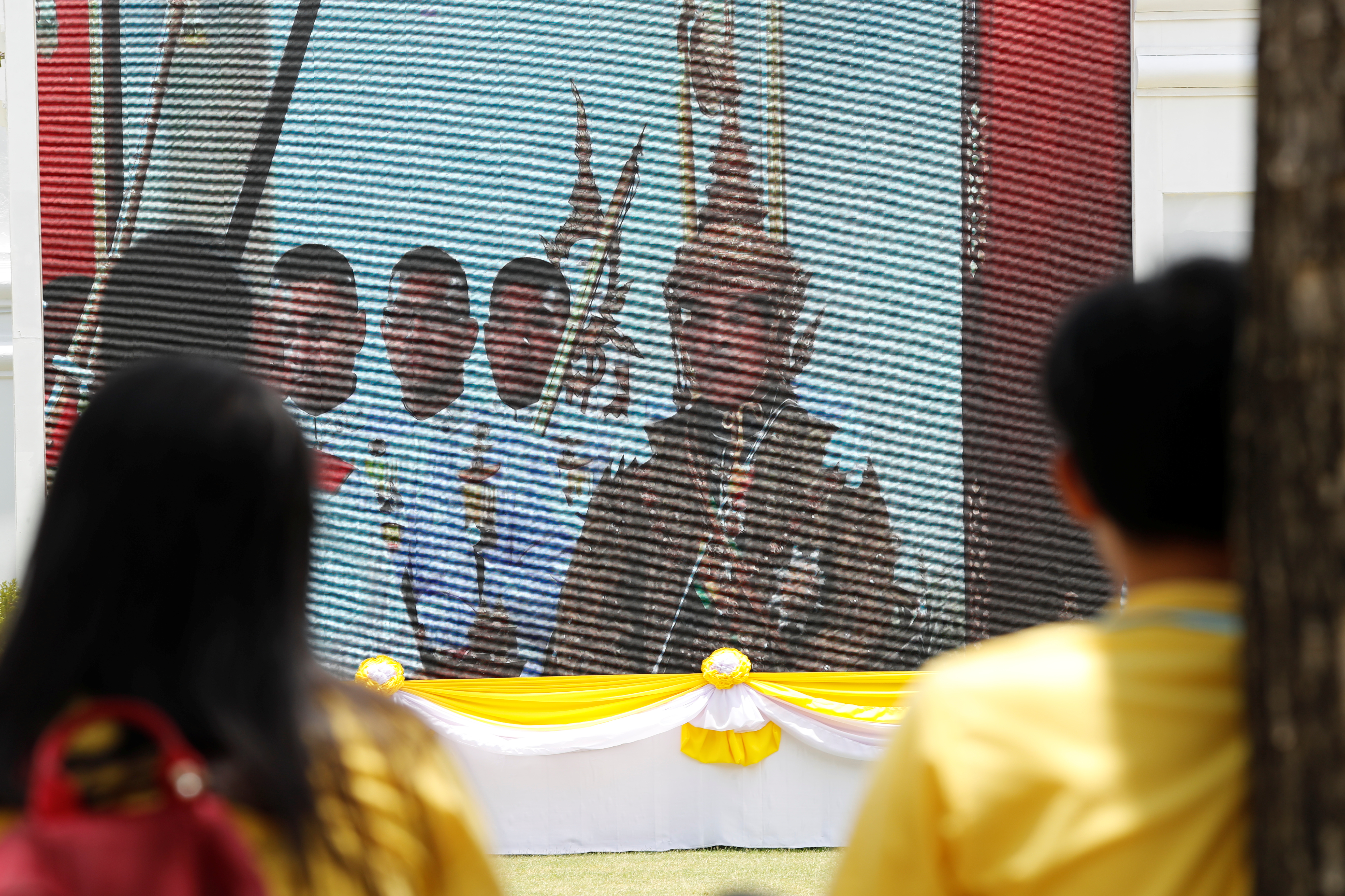 民众透过大荧幕观看泰王哇集拉隆功穿戴上多件王室圣物。-路透社-