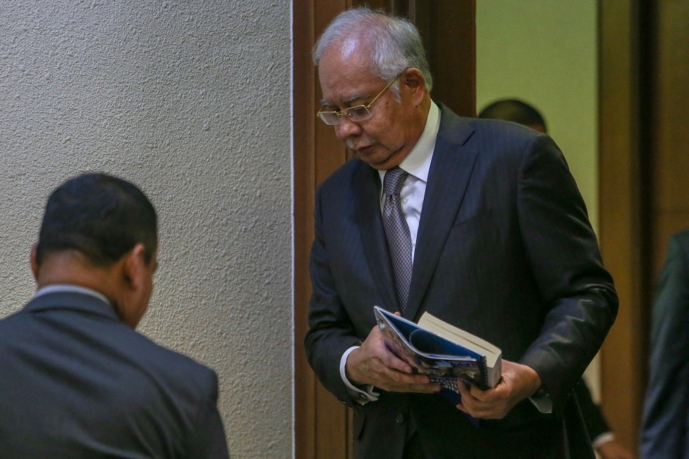 Datuk Seri Najib Razak walks out of the courtroom during lunch break of day 16 of his trial, with a book and what is believed to be BNu00e2u20acu2122s GE14 manifesto hidden underneath in his hands, in Kuala Lumpur May 9, 2019. u00e2u20acu201d Picture by Hari Anggara