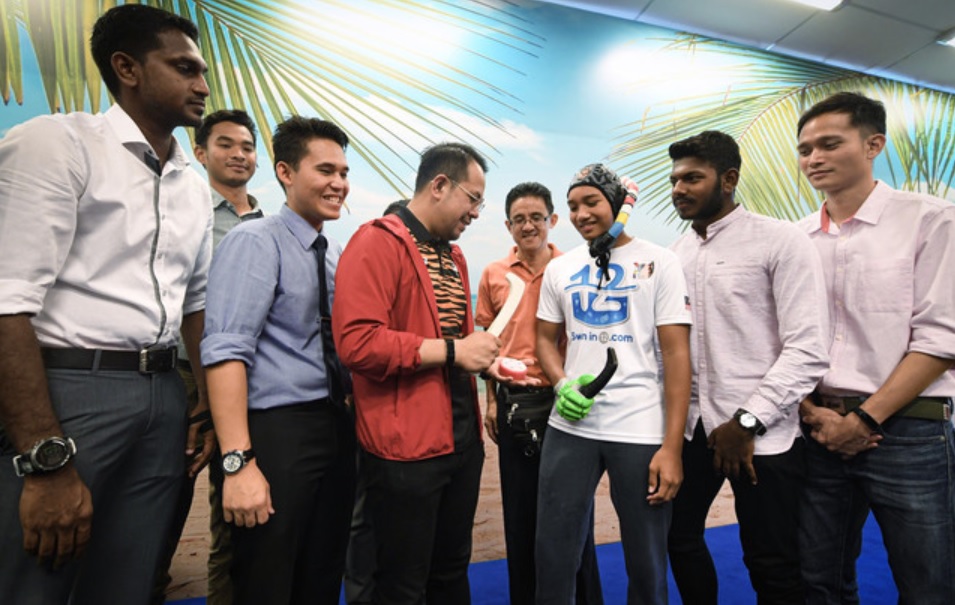 青年及体育部副部长沈志强（中）在巡视新成立的水下钩球队时，获赠一支水下钩球球棍。-马新社-