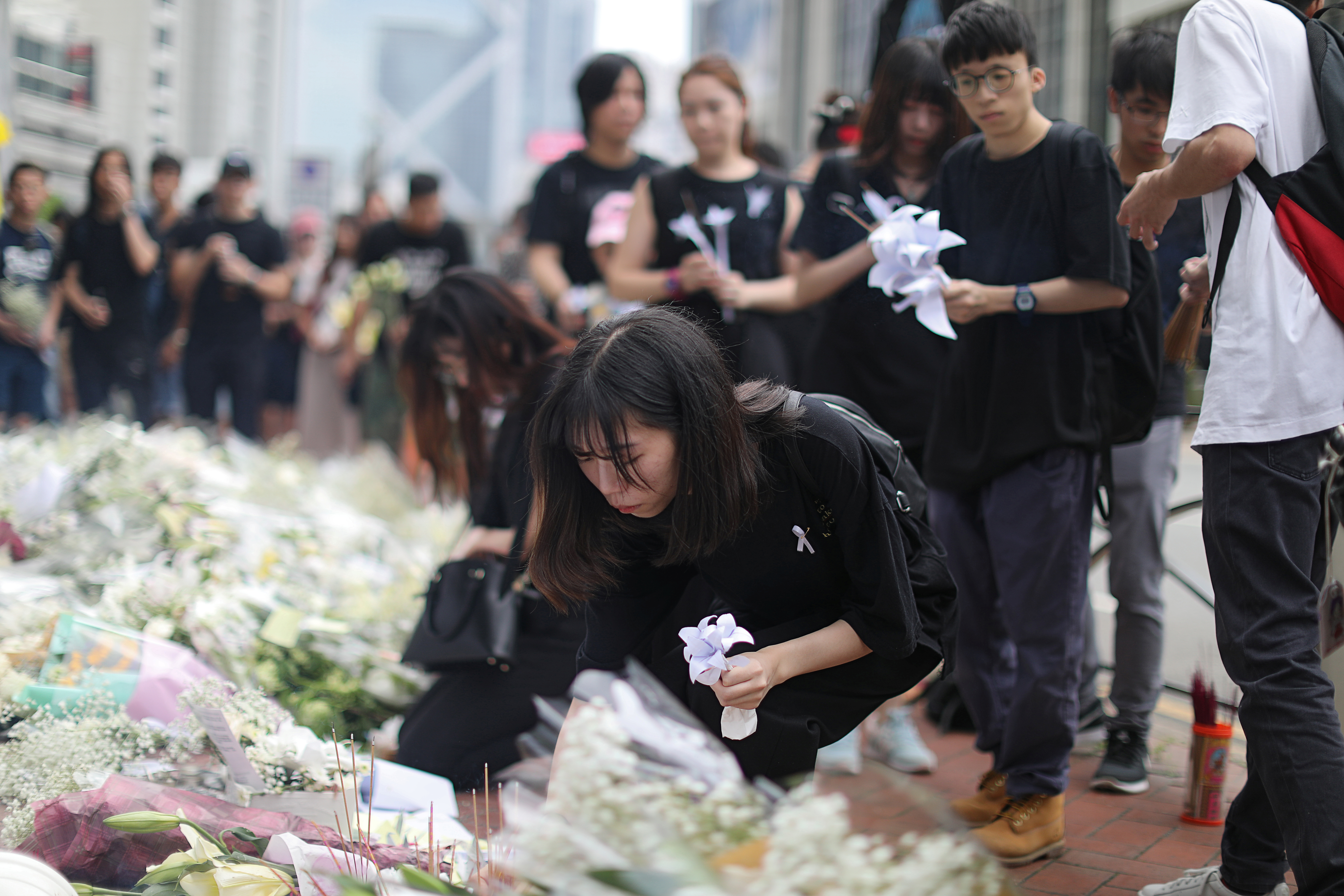 不少黑衣人持白花或纸花到金钟太古广场弔唁周六枉死的反送中男子。-路透社-