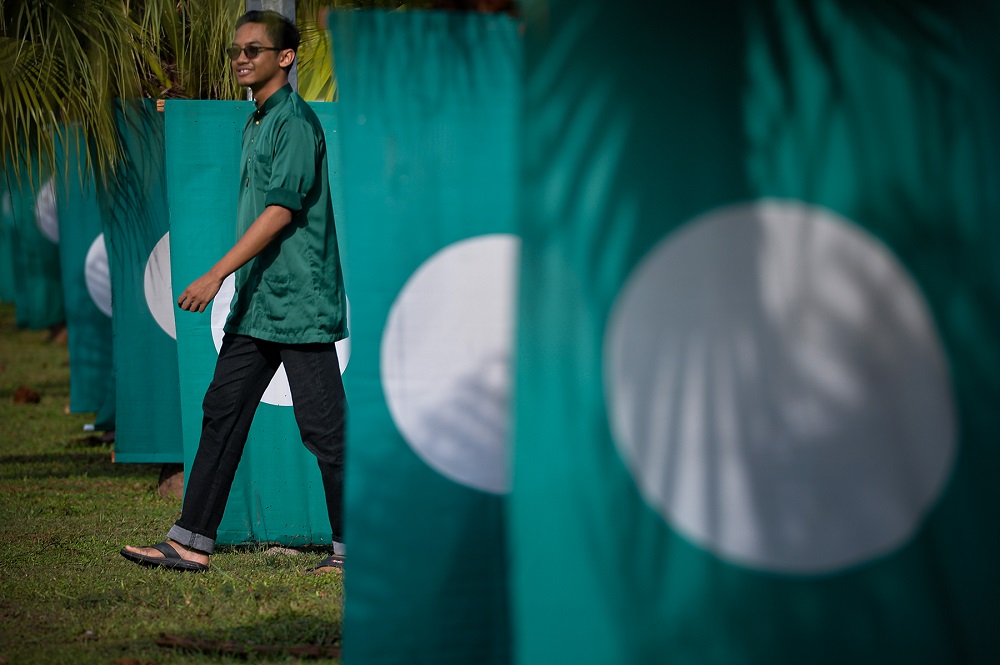 A PAS supporter walks near PAS flags at the 65th Muktamar in Kuantan June 22, 2019. u00e2u20acu201d Picture by Mukhriz Hazim