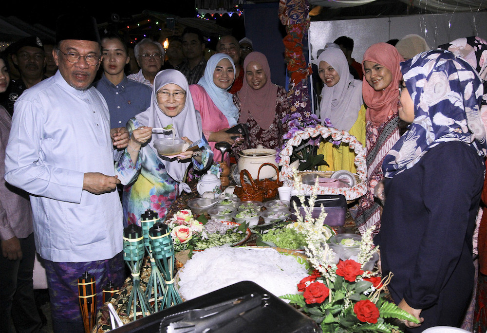 Datuk Seri Dr Wan Azizah Wan Ismail tries some laksa, as her husband Datuk Seri Anwar Ibrahim looks on, during the latteru00e2u20acu2122s Aidilfitri open house in Port Dickson June 15, 2019. u00e2u20acu201d Bernama pic