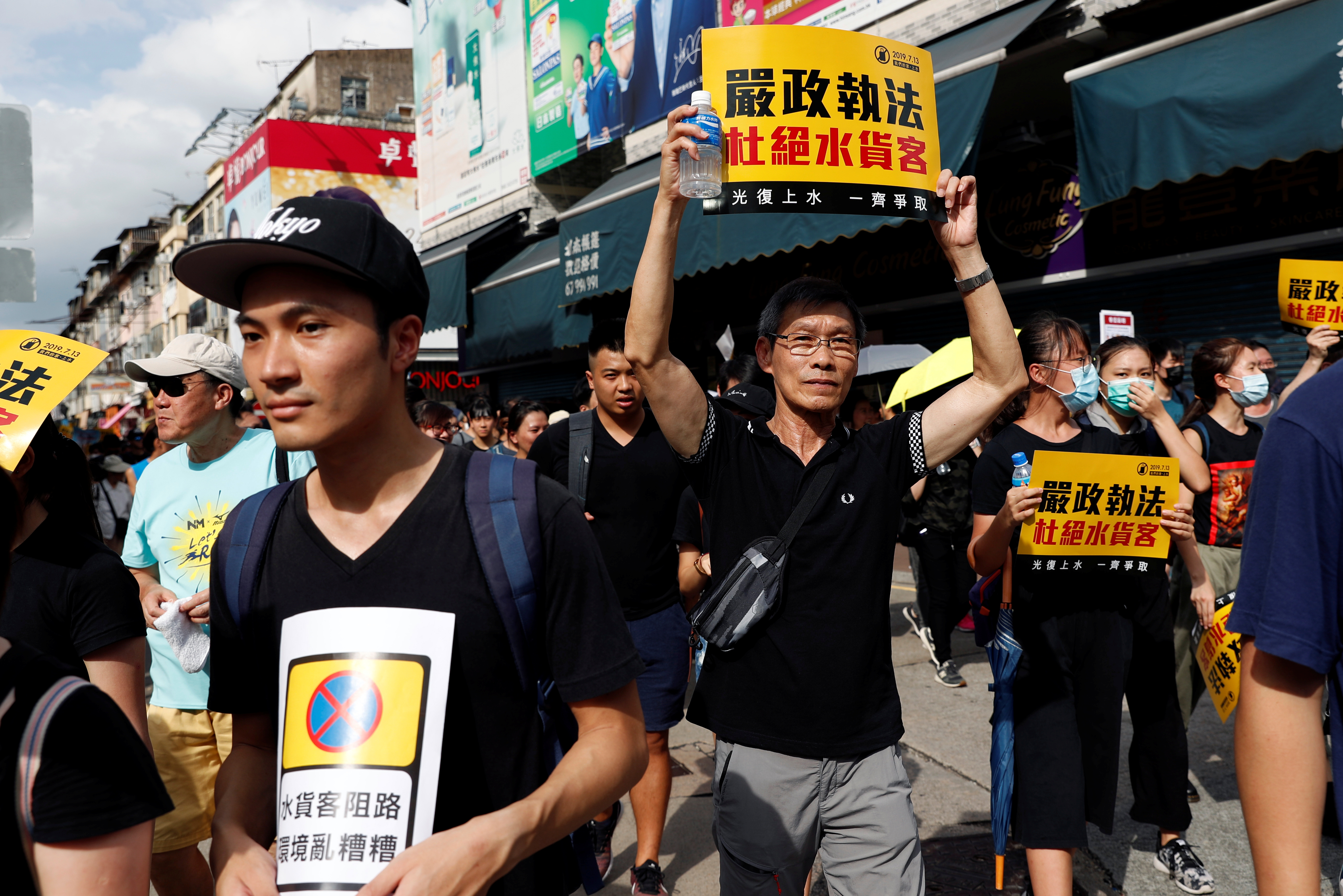香港民众手持标语游行，沿路高喊“光复上水、还我社区”等口号。-路透社-