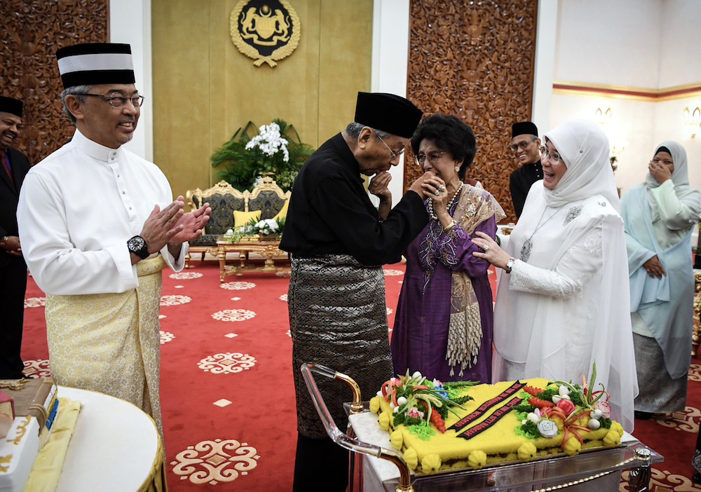 Sultan Abdullah Ahmad Shah smiles as Tun Dr Mahathir Mohamad and Tun Dr Siti Hasmah Mohd Ali feed each other cake during a surprise birthday party at Istana Negara in Kuala Lumpur July 11, 2019. u00e2u20acu201d Bernama pic