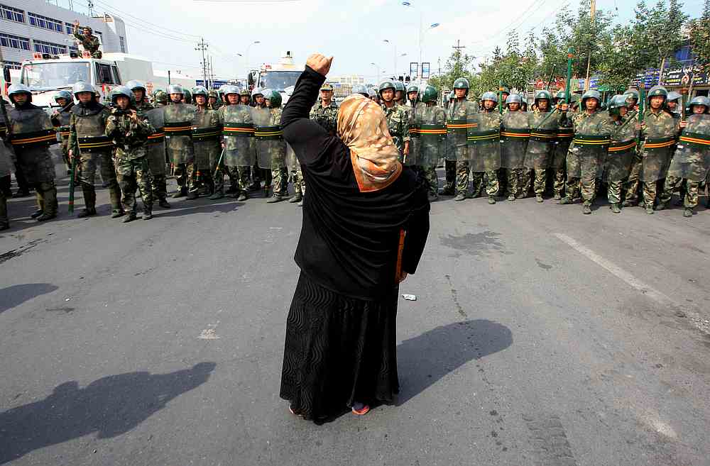A local woman on a crutch shouts at Chinese paramilitary police wearing riot gear as a crowd of angry locals confront security forces in Urumqi, Xinjiang Autonomous Region, China July 7, 2009. u00e2u20acu201d Reuters pic