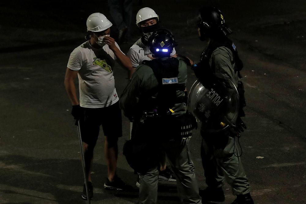 Men in white T-shirts and carrying poles talk to riot police in Yuen Long after attacking anti-extradition bill demonstrators at a train station in Hong Kong July 22, 2019. u00e2u20acu201d Reuters pic